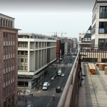 Blick über eine verkehrsreiche Stadtstraße mit mehrspurigen Fahrbahnen, gesäumt von modernen Geschäftshäusern unter bedecktem Himmel, im Kontext der Jobvermittlung durch Staff Eins.
